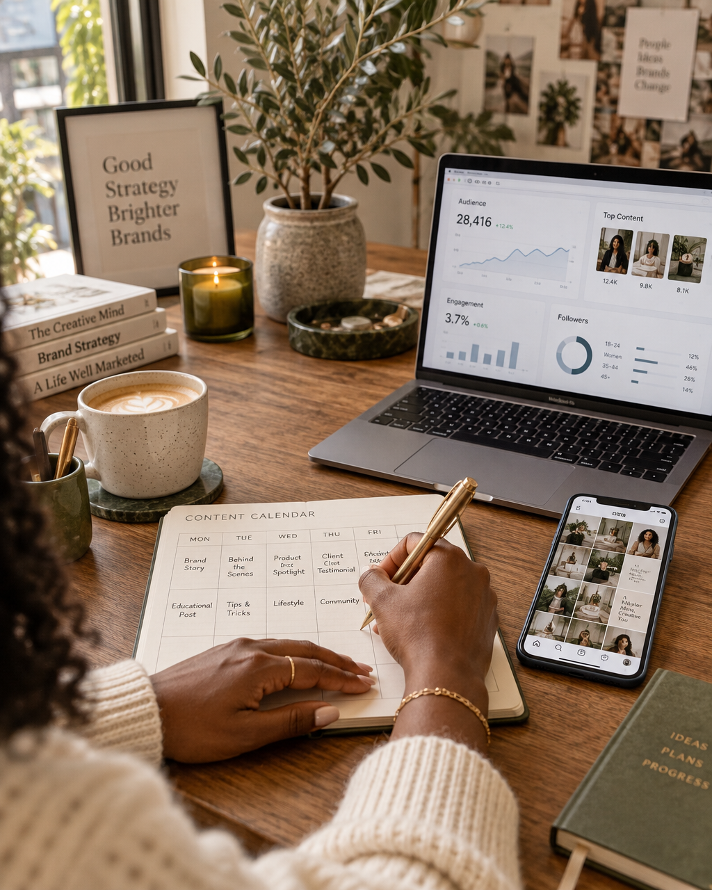 Stephanie's hands in a cream knit sweater writing in a content calendar beside a laptop showing social media analytics